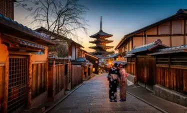 two women in purple and pink kimono standing on street